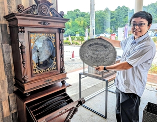 アンティークオルゴールの前で、演奏用のディスクを手にするオーナー・酈さん＝丹波篠山市東吹