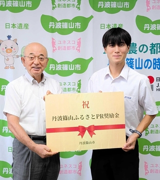 日本ジュニアトライアスロン選手権に出場し、「丹波篠山ふるさとＰＲ奨励金」を受け取った河口航生さん（右）＝丹波篠山市役所