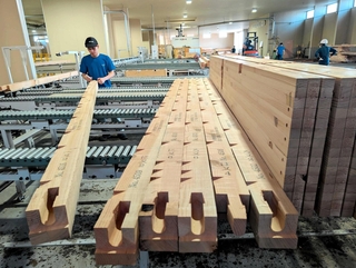 自動生産ラインの加工機で切削された建材をチェックする従業員＝丹波篠山市北