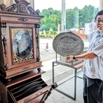 アンティークオルゴールの前で、演奏用のディスクを手にするオーナー・酈さん＝丹波篠山市東吹