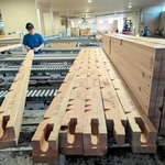自動生産ラインの加工機で切削された建材をチェックする従業員＝丹波篠山市北