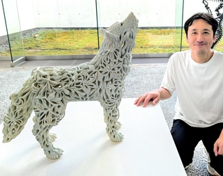 自作「朧気（狼）」の横に並ぶ秋永邦洋さん＝兵庫陶芸美術館