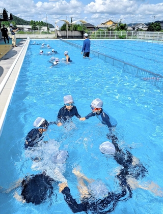 ２学期に始まった水泳の授業で、水中に潜る練習をする小学１、２年の児童たち＝城東小学校