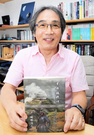 新作「黒井城燃ゆ」を手にする瞬那浩人さん＝丹波市春日町黒井