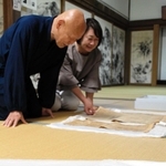 びょうぶから見つかった新聞を見る日置義紹住職（左）ら＝丹波市氷上町御油