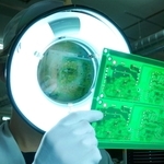 １枚ずつ電子基板をチェックする従業員。最新の技術と人の目による入念な確認が品質の高さを守っている＝丹波市氷上町石生