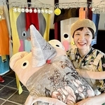 自作のぬいぐるみアートを抱き、洗濯物をイメージした新作「素風快晴」の前に座る造形作家あさうみまゆみさん＝丹波篠山市河原町