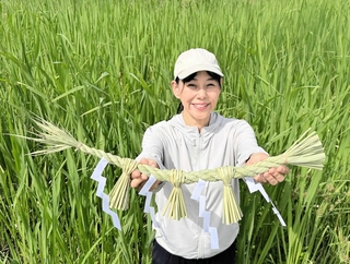 マコモ畑の前で、マコモで自作したしめ縄を手にする生野由美さん＝丹波篠山市油井