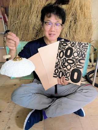 丹波篠山ですいた和紙を手にする大西祐一郎さん。和紙を活字で印刷し装飾したり、ランプシェードにしたりする試みも＝丹波篠山市黒田