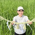 マコモ畑の前で、マコモで自作したしめ縄を手にする生野由美さん＝丹波篠山市油井