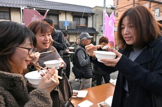 猪肉を煮込んだ「ぼたん汁」を味わう観光客や地元住民ら＝丹波篠山市北新町