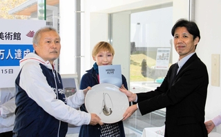 西垣鉄也館長（右）から記念品として丹波焼の皿を受け取る前田数夫さん（左）。中央は妻弘子さん＝兵庫陶芸美術館