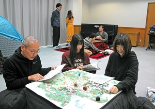 リハーサルでこたつを搬入し、ゲームや読書を楽しむ人たち＝丹波市氷上町常楽