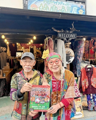 「だいじょうぶ屋」の前で、４０周年セレモニーのチラシを手にする岩下八司さん（左）と妻・啓子さん＝丹波篠山市呉服町