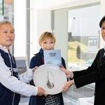 西垣鉄也館長（右）から記念品として丹波焼の皿を受け取る前田数夫さん（左）。中央は妻弘子さん＝兵庫陶芸美術館