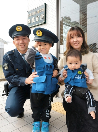 畑駐在所に勤務する岸田圭記さん（左）と家族たち。息子の悠寿ちゃん（中央）と伊栞ちゃん（右手前）が着る警察風のベストは妻・真海さんの手製で、愛らしい姿が地域住民を癒やしている＝兵庫県丹波篠山市畑宮