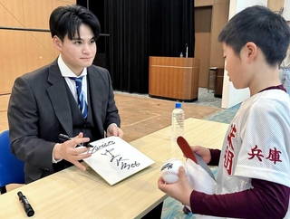 地元出身の中森俊介投手に、色紙へサインしてもらう少年野球チームの選手＝市民センター