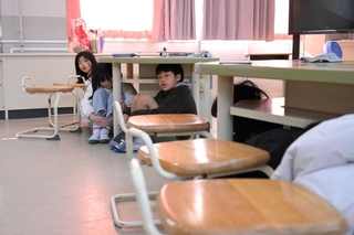 机の下に潜り込み、頭を守る子どもら＝北小学校