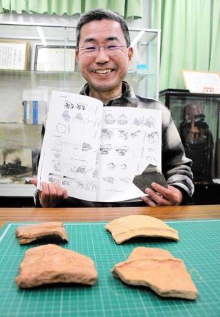 報告書を手にする東昭吾さん。手前には発見した破片の一部が並ぶ＝丹波市内