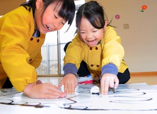 ペンで黒いラインを引き、小さなロボットを走らせて楽しむ園児たち＝丹波市氷上町常楽