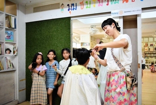 バンコクのスラム街の施設で無料ヘアカットをする星宗果歩さん（右）＝本人提供