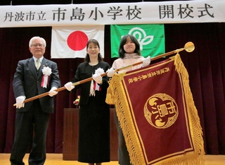 真新しい校旗を受け取り、記念写真に収まる児童代表ら＝市島小学校