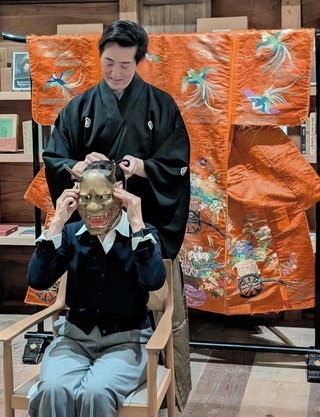 能楽師の上田宜照さんに能面を着けてもらう女性＝豆家