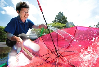 傘を洗う社員の河原政子さん。「みんなに快適な環境がいいでしょ」とほほ笑み、ブラシで丁寧に汚れを落とす＝オータニにしきカントリークラブ