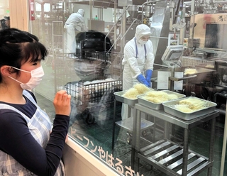 見学者用の通路から工程を見る来場者＝ケンミン篠山工場