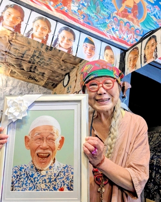 バングラデシュの子どもたちの写真の前で、岩下八司さんの遺影を手にする妻・啓子さん＝丹波篠山市呉服町
