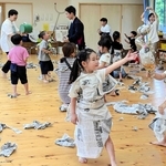 新聞紙で作った衣装を着たり、丸めて投げたりして遊ぶ園児ら＝こんだ認定こども園