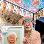 バングラデシュの子どもたちの写真の前で、岩下八司さんの遺影を手にする妻・啓子さん＝丹波篠山市呉服町
