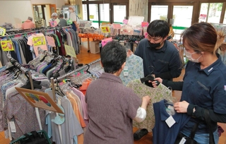 高齢者施設の食堂を会場に開かれた出張販売。利用者の女性がオオツキのスタッフと一緒に服選びを楽しんでいた＝６月、豊岡市日高町祢布