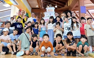 大きなバースデーケーキを前に記念撮影する入館者やスタッフら＝篠山チルドレンズミュージアム（提供）
