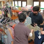 高齢者施設の食堂を会場に開かれた出張販売。利用者の女性がオオツキのスタッフと一緒に服選びを楽しんでいた＝６月、豊岡市日高町祢布