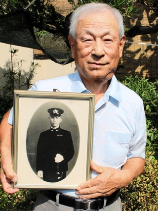 戦死した父・勉さんの遺影を抱く角悟さん＝丹波市柏原町北中