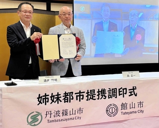 オンライン調印式で、調印書を手にする２市の市長ら＝篠山城大書院