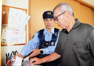 電話機に取り付けた録音機の状態を確かめる菅野秀昭警部補（左）＝丹波篠山市内