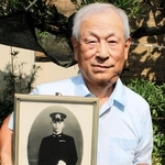 戦死した父・勉さんの遺影を抱く角悟さん＝丹波市柏原町北中