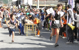 過去の大会で、バトン代わりの棒を手に走る出場者＝丹波市青垣町佐治