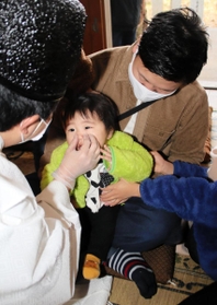 宮司に鼻をつままれる男児＝高砂市北浜町西浜、大歳神社