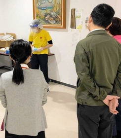 ジャパンハートから派遣され、東加古川病院の職員に防護服の処分方法を説明する看護師（奥）＝加古川市平岡町新在家（ジャパンハート提供）