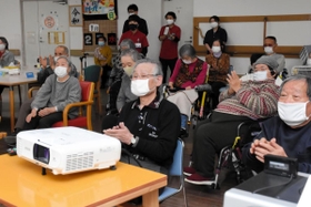 スクリーンに向かって拍手を送る利用者＝兵庫県稲美町国安、介護老人保健施設サンライズ