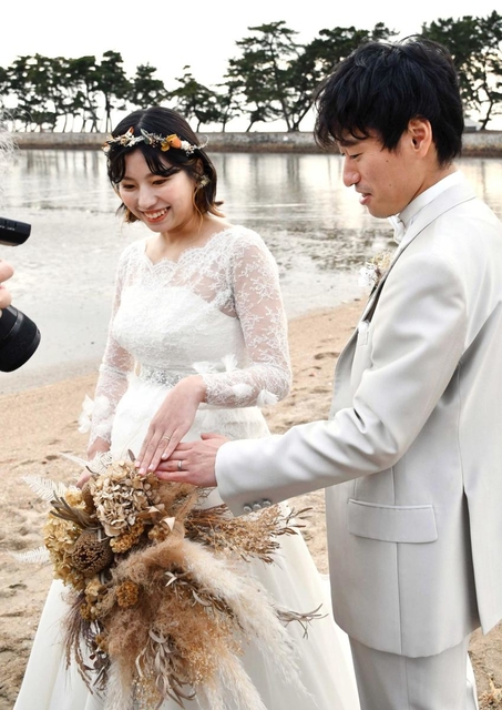 結婚指輪を撮影してもらう安東さん夫妻＝県立高砂海浜公園（高砂市提供）