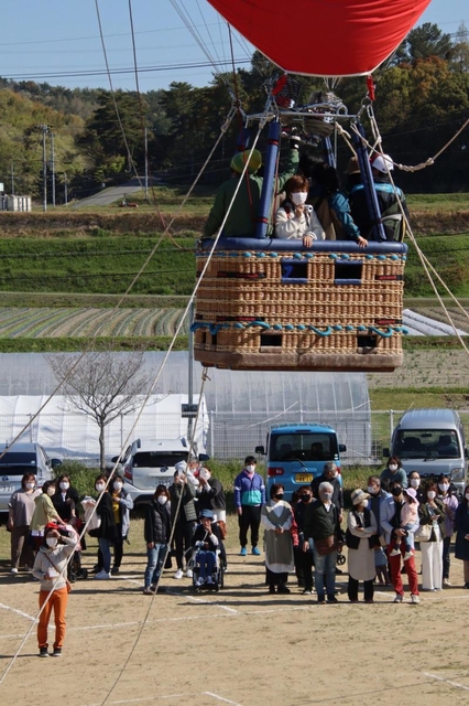 少しずつ高度が上がる熱気球。地上からも手を振ったり、記念撮影したりして楽しんだ＝加古川養護学校