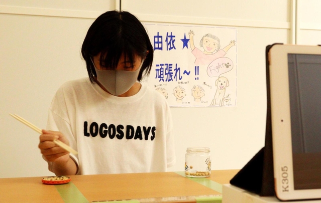 箸で豆を素早く移動させ、ギネス世界記録に挑む坂崎由依さん＝いなみっこ広場