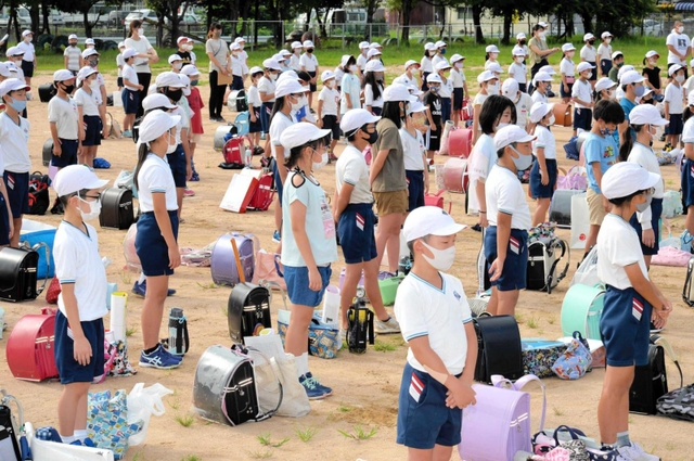 ランドセルや夏休みの宿題を脇に置いて始業式に臨む児童＝中筋小学校