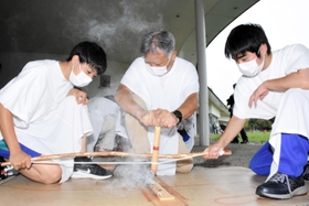力を合わせ、弓ぎり式で火をおこす参加者＝播磨町大中１、県立考古博物館