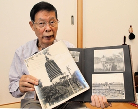 中国・鞍山市にいた頃の写真を示しながら、当時の体験を語る堀川哲男さん＝加古川市