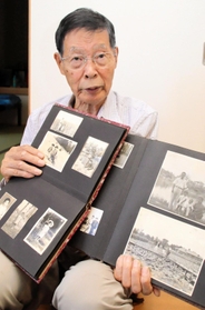 中国・鞍山市にいた頃の写真を示しながら、当時の体験を語る堀川哲男さん＝加古川市